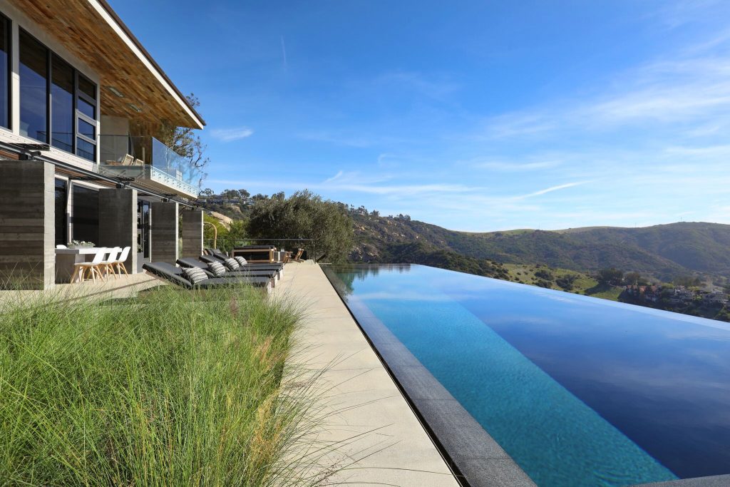 Inspiration for a large contemporary backyard concrete paver and rectangular infinity hot tub remodel in Orange County