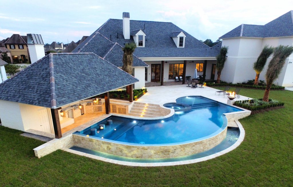 Inspiration for a large contemporary backyard custom-shaped infinity pool house remodel in New Orleans with decking