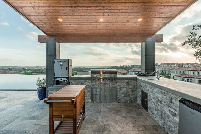 Inspiration for a large contemporary backyard stone patio kitchen remodel in San Diego with a pergola