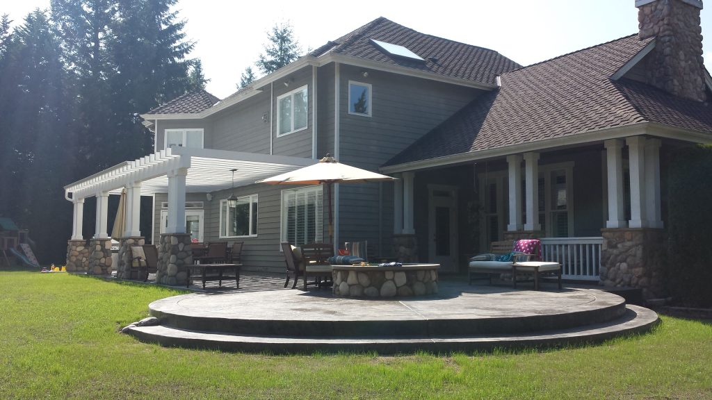 Inspiration for a large craftsman backyard stamped concrete patio kitchen remodel in Seattle with a pergola