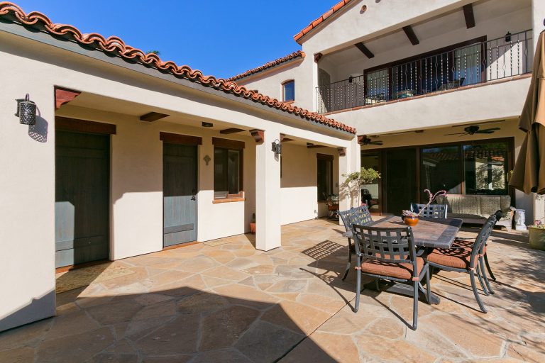 Inspiration for a large mediterranean courtyard stone patio kitchen remodel in San Diego with a roof extension