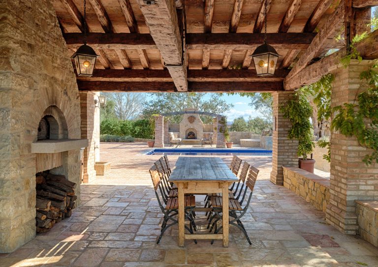 Inspiration for a large mediterranean side yard stone patio kitchen remodel in Orange County with a roof extension