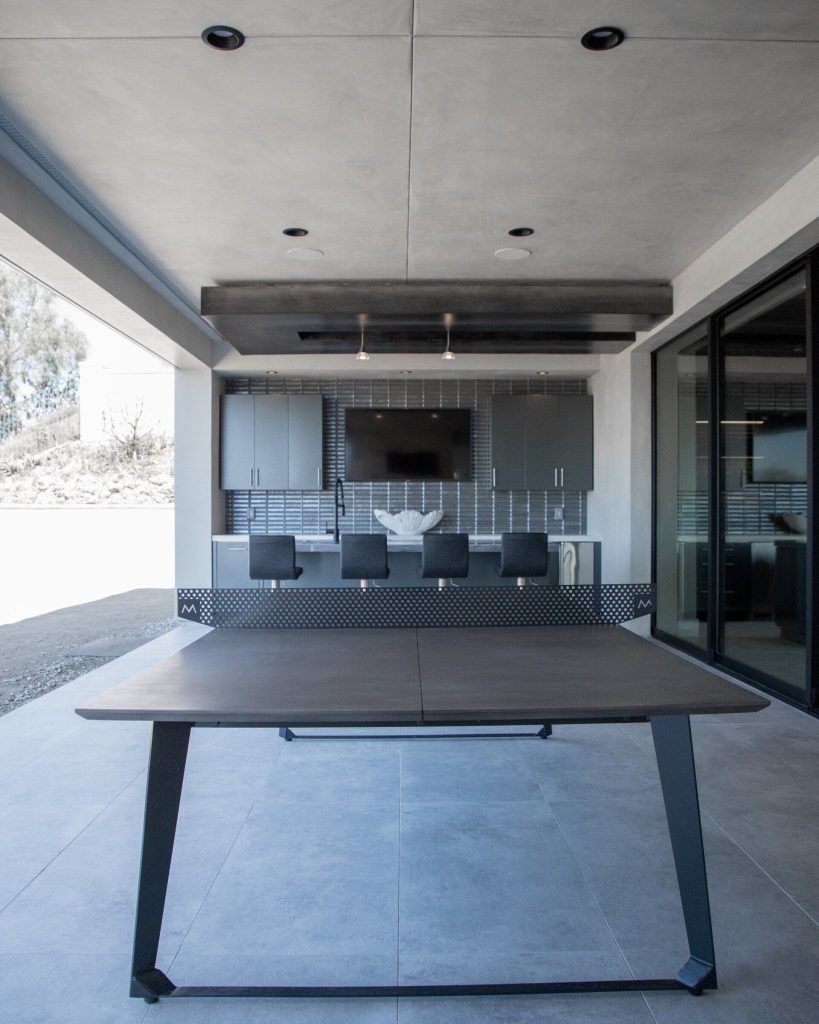 Inspiration for a large modern backyard stamped concrete patio kitchen remodel in Orange County with a roof extension
