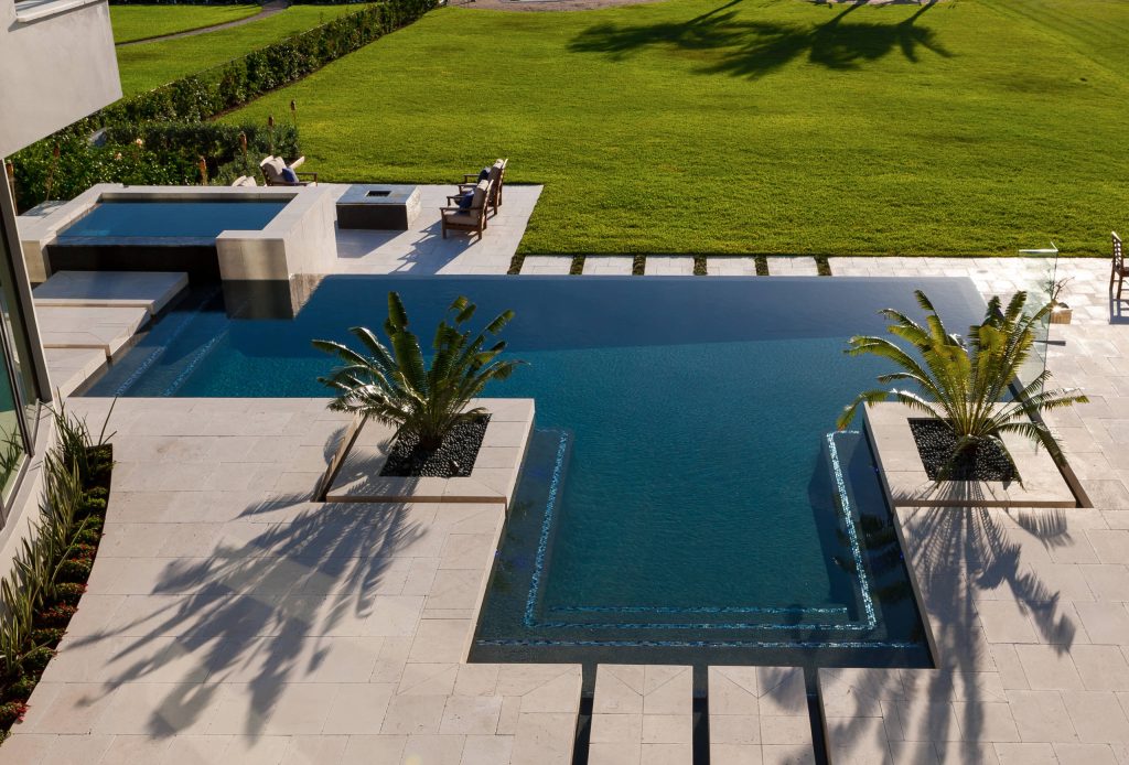 Inspiration for a large modern backyard stone and custom-shaped infinity hot tub remodel in Miami