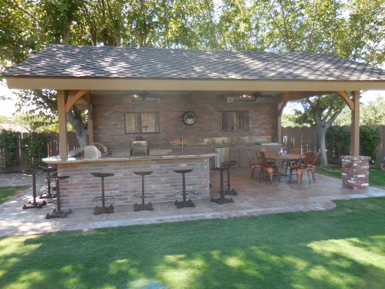 Inspiration for a large rustic backyard stamped concrete patio kitchen remodel in Other with a pergola