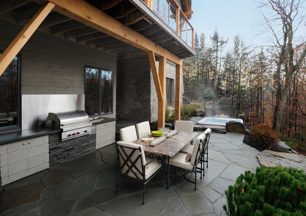Inspiration for a large rustic backyard stamped concrete patio kitchen remodel in Other with a roof extension