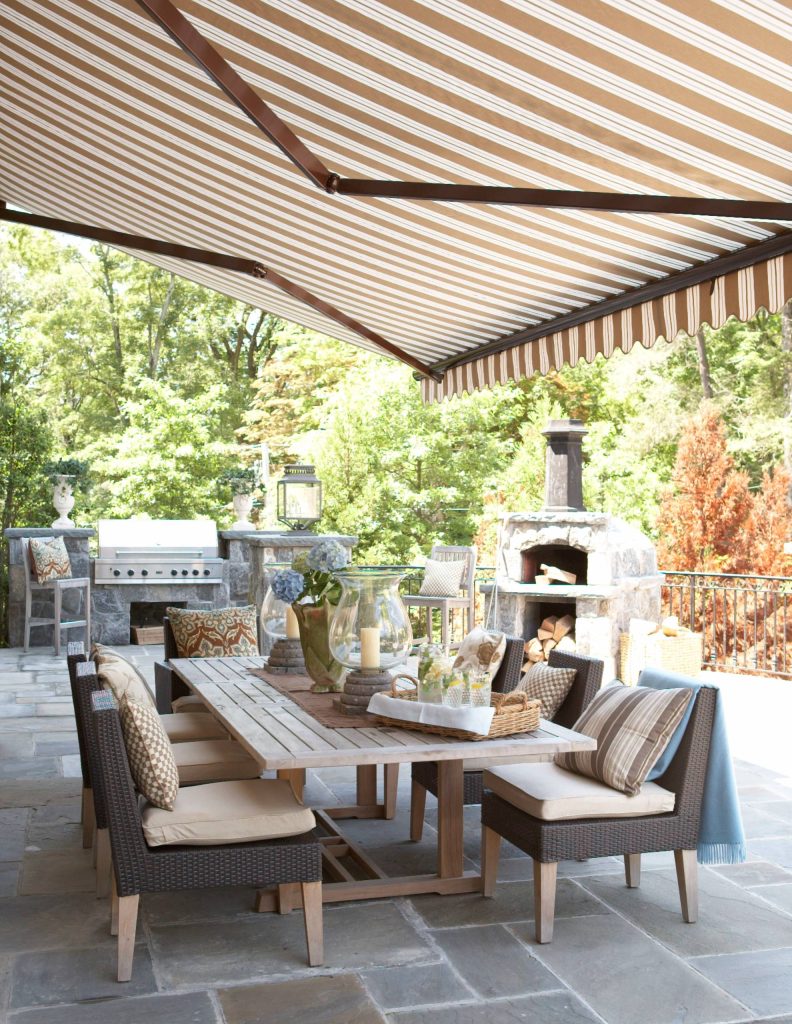 Inspiration for a large timeless backyard concrete paver patio kitchen remodel in New York with an awning