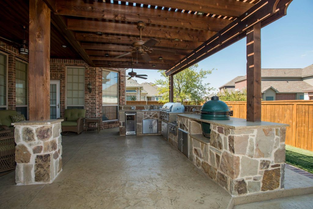 Inspiration for a large timeless backyard stamped concrete patio kitchen remodel in Dallas with a pergola