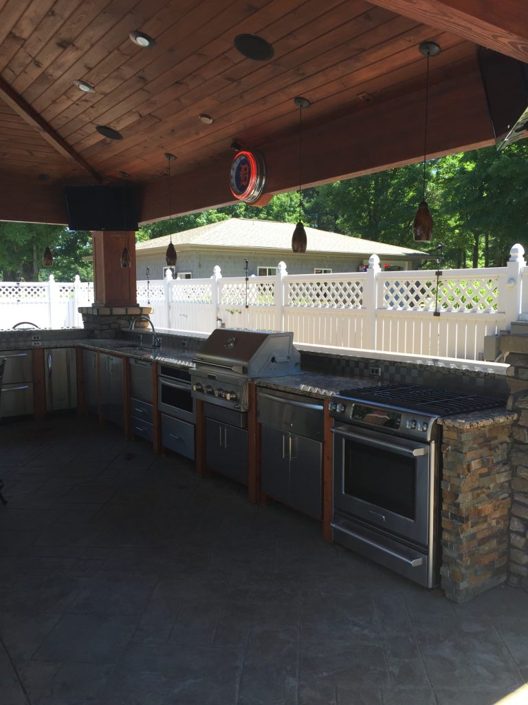 Inspiration for a large timeless backyard stamped concrete patio kitchen remodel in Grand Rapids with a pergola