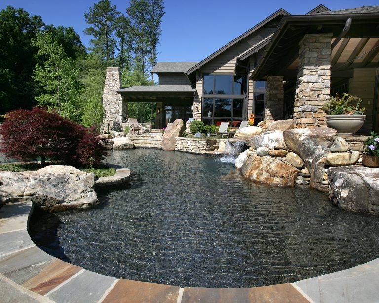 Inspiration for a large timeless backyard stone and custom-shaped infinity hot tub remodel in Other