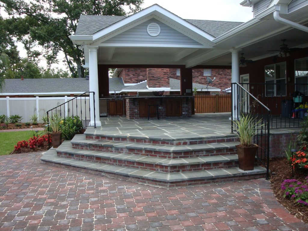 Inspiration for a large timeless backyard stone patio kitchen remodel in New Orleans with a roof extension