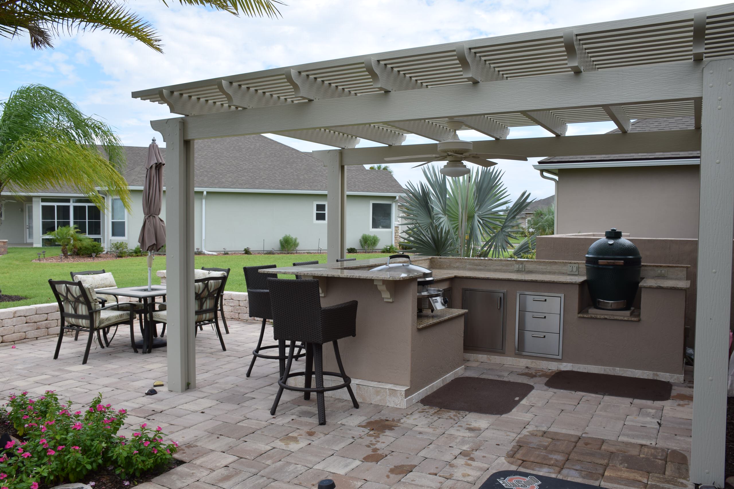 Inspiration for a large transitional backyard concrete paver patio kitchen remodel in Jacksonville with a pergola