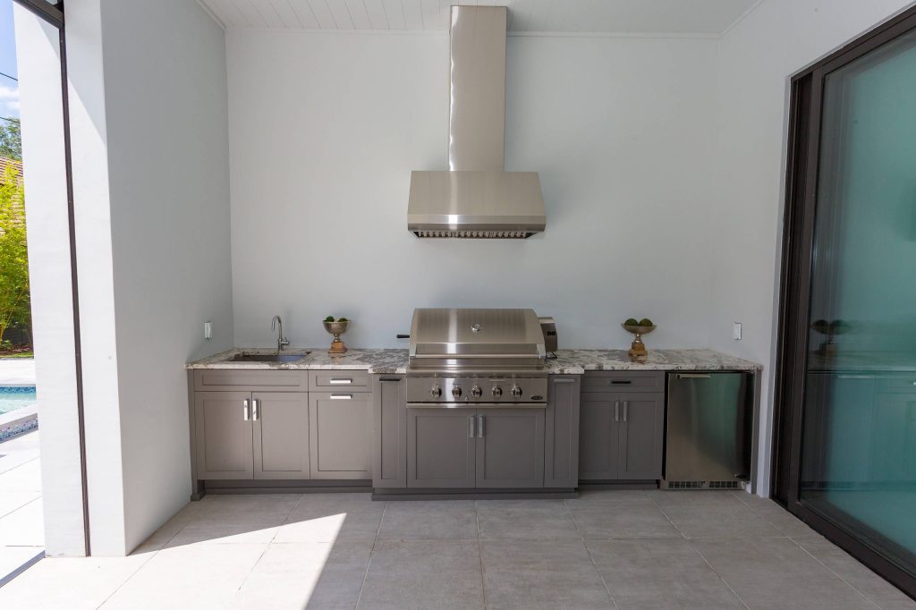 Inspiration for a large transitional backyard stone patio kitchen remodel in Orlando with a roof extension