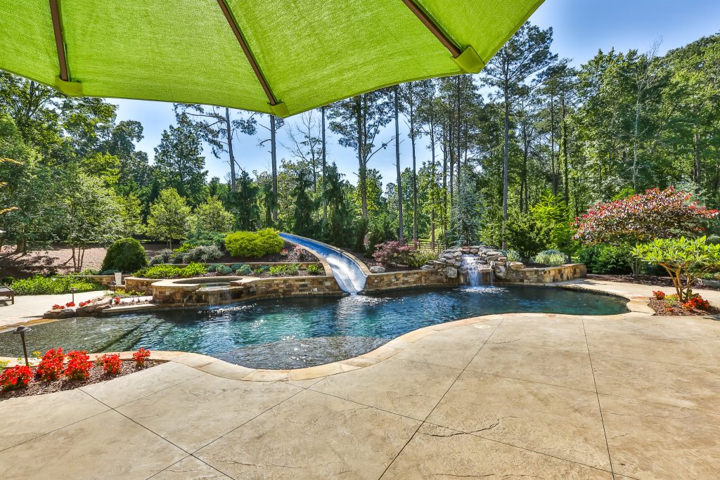 Inspiration for a large tropical backyard custom-shaped natural water slide remodel in Atlanta with decking
