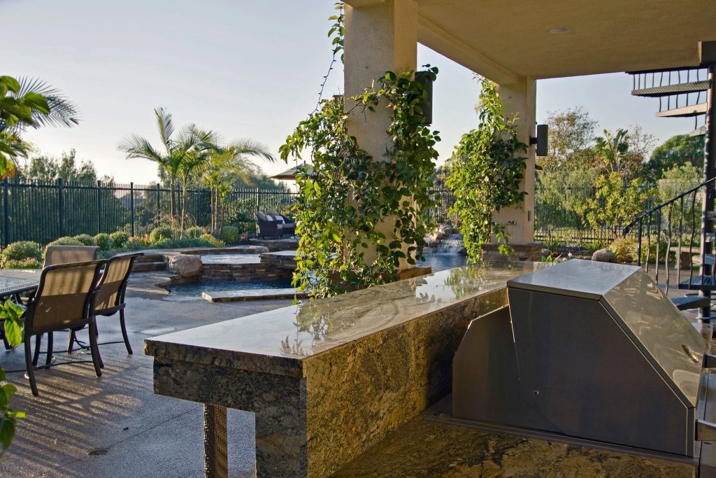 Inspiration for a large tropical backyard patio kitchen remodel in Orange County with a roof extension