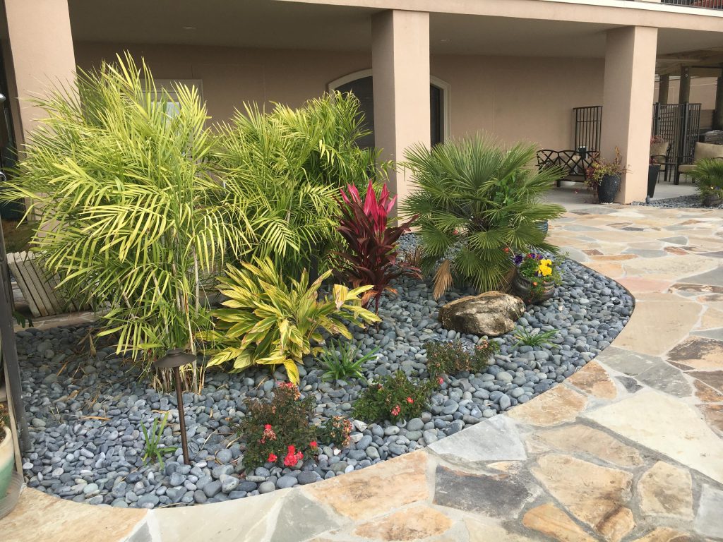 Inspiration for a large tropical backyard stone patio kitchen remodel in Miami with a roof extension