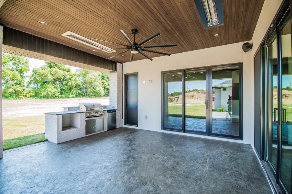 Inspiration for a mid-sized contemporary backyard stamped concrete patio kitchen remodel in Other with a roof extension