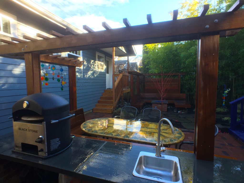 Inspiration for a mid-sized eclectic backyard brick patio kitchen remodel in Seattle with a pergola