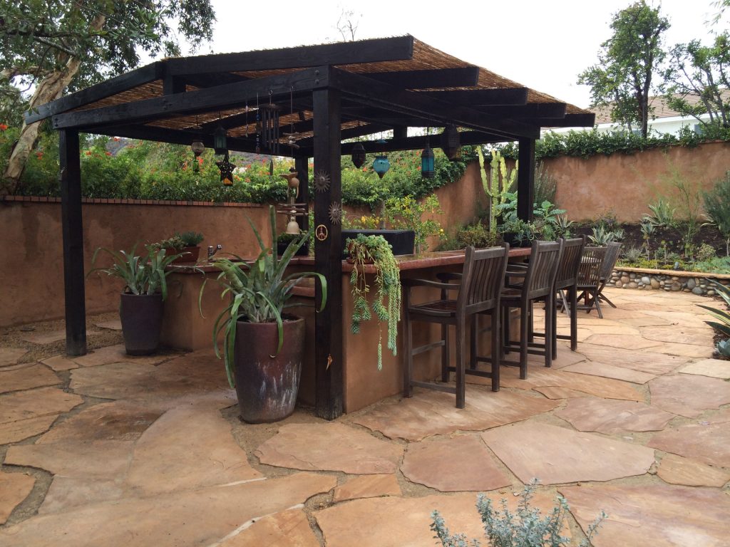 Inspiration for a mid-sized mediterranean backyard stone patio kitchen remodel in Los Angeles with a pergola