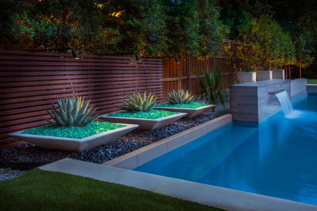 Inspiration for a mid-sized modern backyard rectangular pool fountain remodel in Dallas with decking