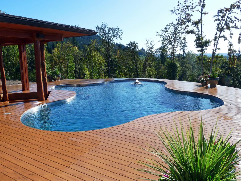 Inspiration for a mid-sized rustic backyard custom-shaped aboveground pool fountain remodel in Other with decking