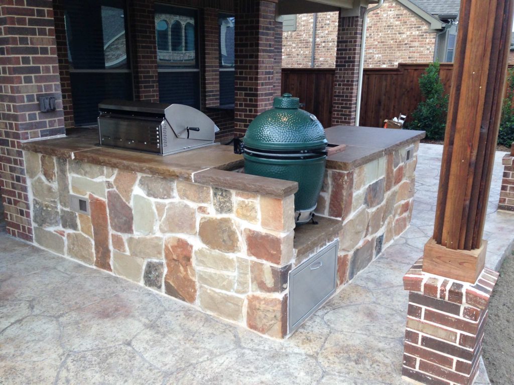 Inspiration for a mid-sized rustic backyard stamped concrete patio kitchen remodel in Dallas with an awning