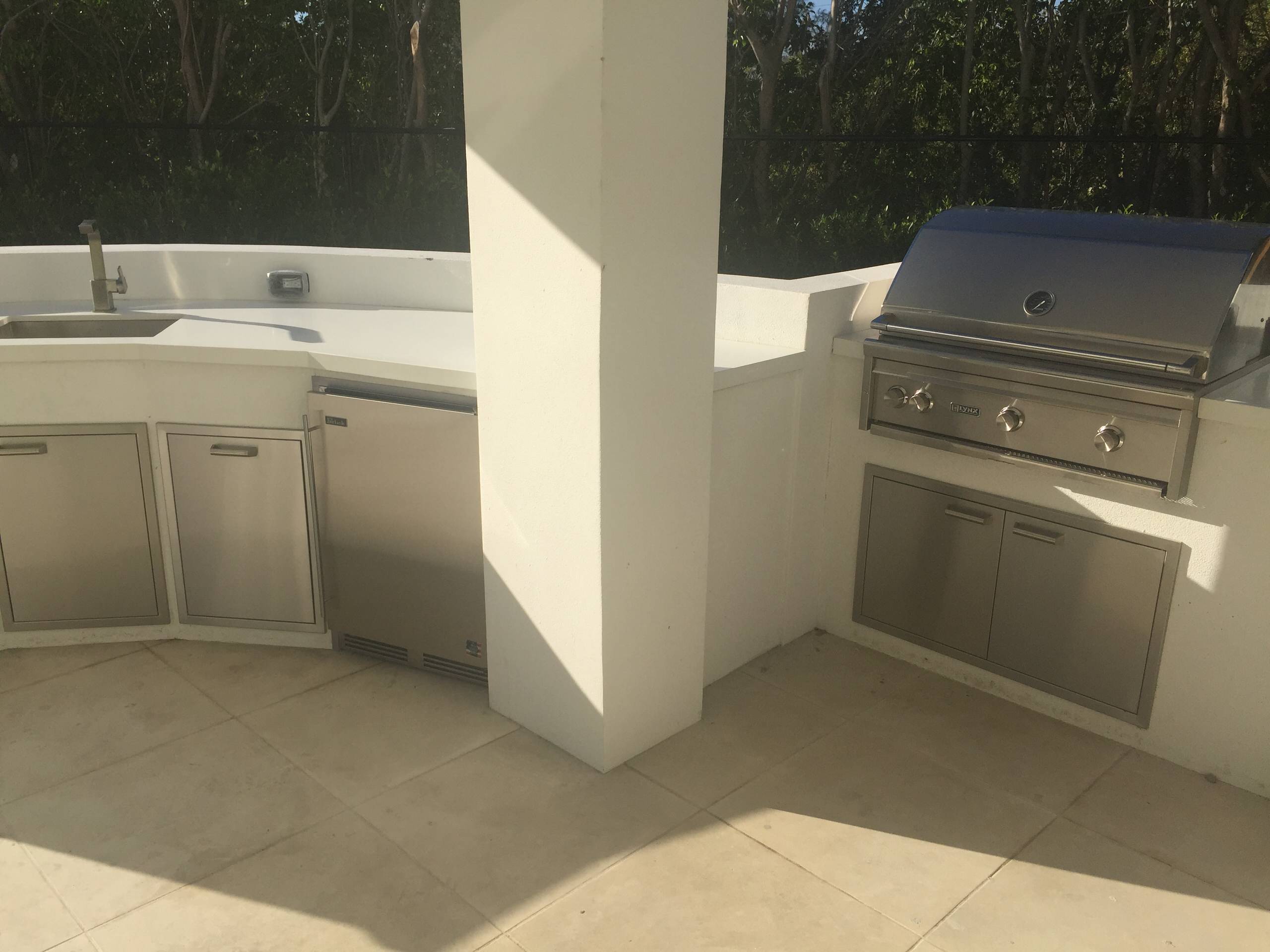 Island style backyard stone patio kitchen photo in Miami with a roof extension