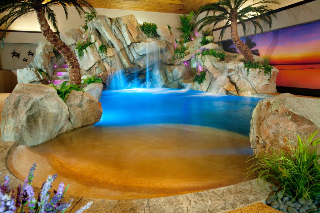 Lagoon style pool with beach entry, rock waterfall, rock table and 20' rock slide by Shehan Pools
