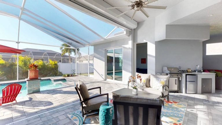 Large beach style backyard concrete paver patio kitchen photo in Miami with a gazebo