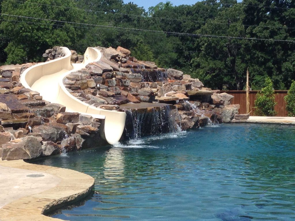 Large custom waterfall with custom slide. Large diving pool with beach entry and spa.