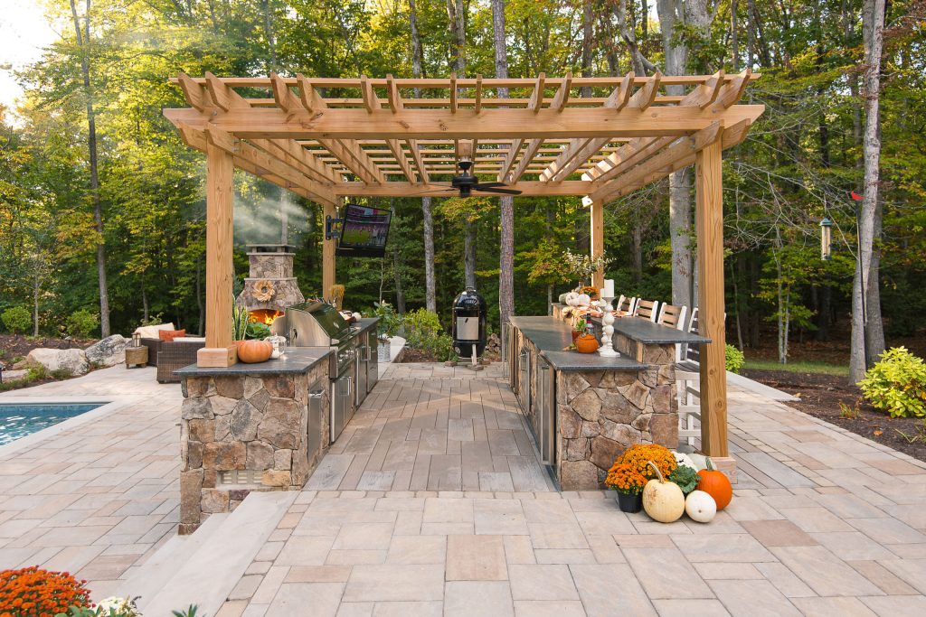 Large elegant backyard concrete paver patio kitchen photo in Richmond with a pergola