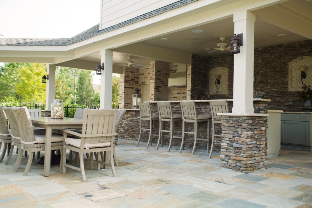 Large elegant backyard stone patio kitchen photo in Houston with a roof extension