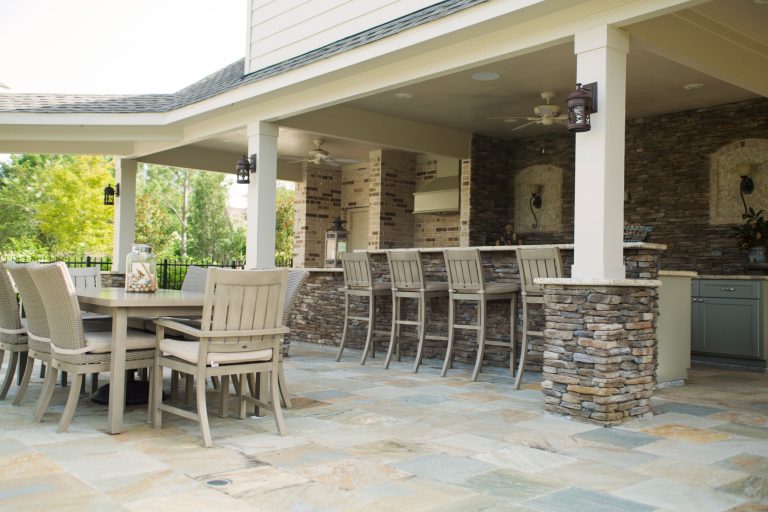 Large elegant backyard stone patio kitchen photo in Houston with a roof extension