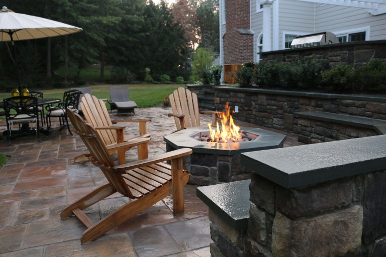 Large elegant backyard stone patio kitchen photo in New York with a pergola