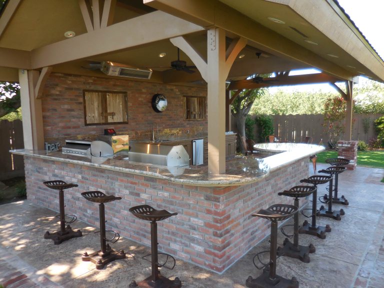 Large farmhouse backyard stamped concrete patio kitchen photo in Other with a pergola