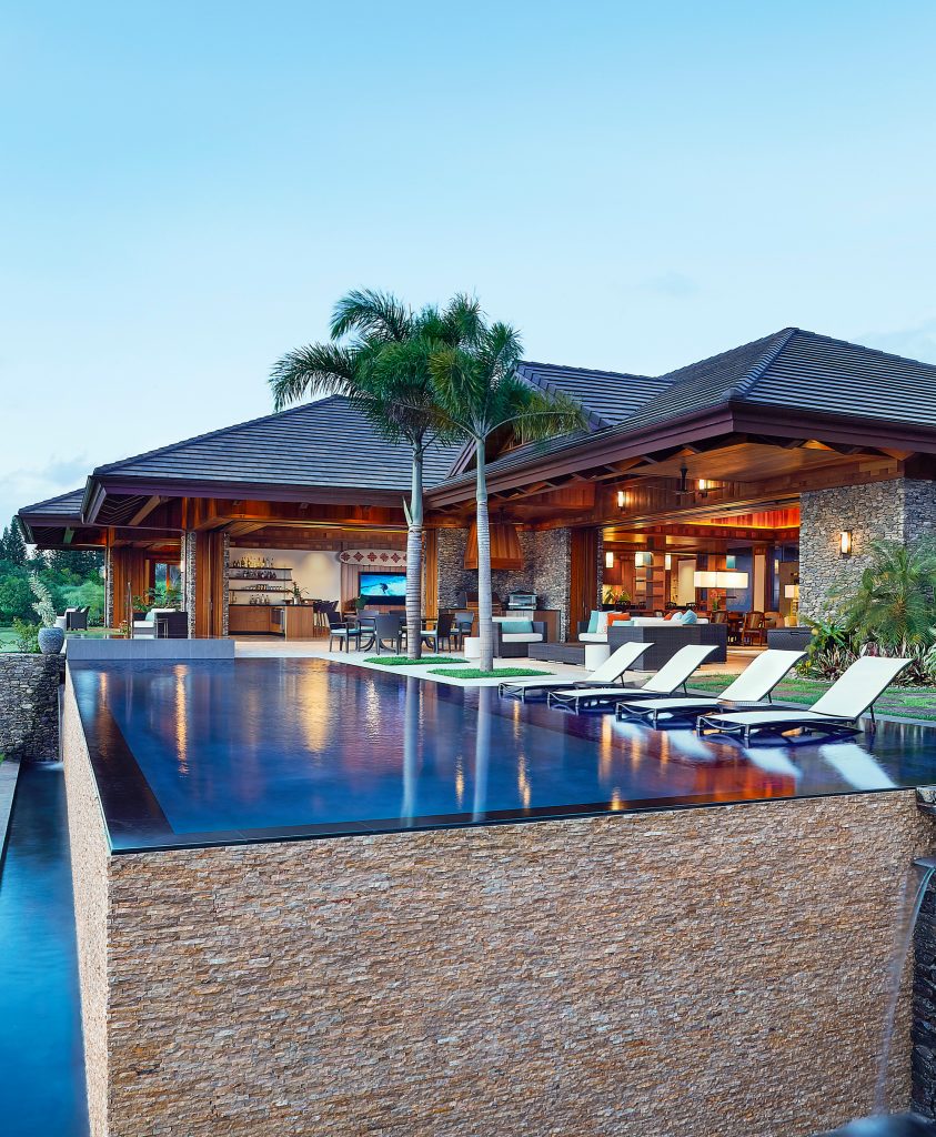 Large island style backyard rectangular and stone infinity hot tub photo in Hawaii