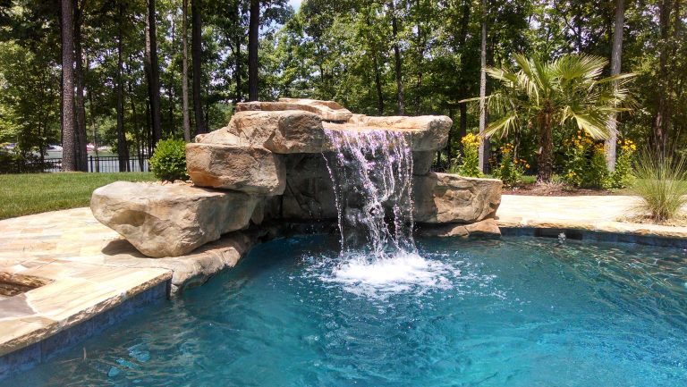 Large island style backyard stone and custom-shaped pool fountain photo in Charlotte