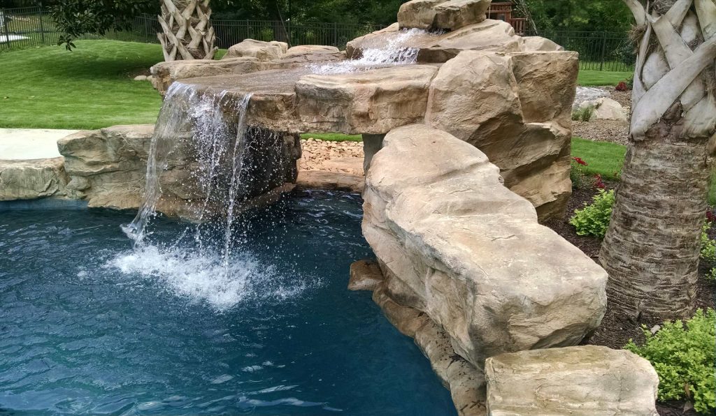 Large island style backyard stone and custom-shaped pool fountain photo in Charlotte