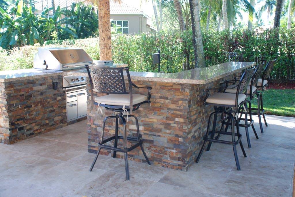 Large island style backyard stone patio kitchen photo in Miami with a gazebo