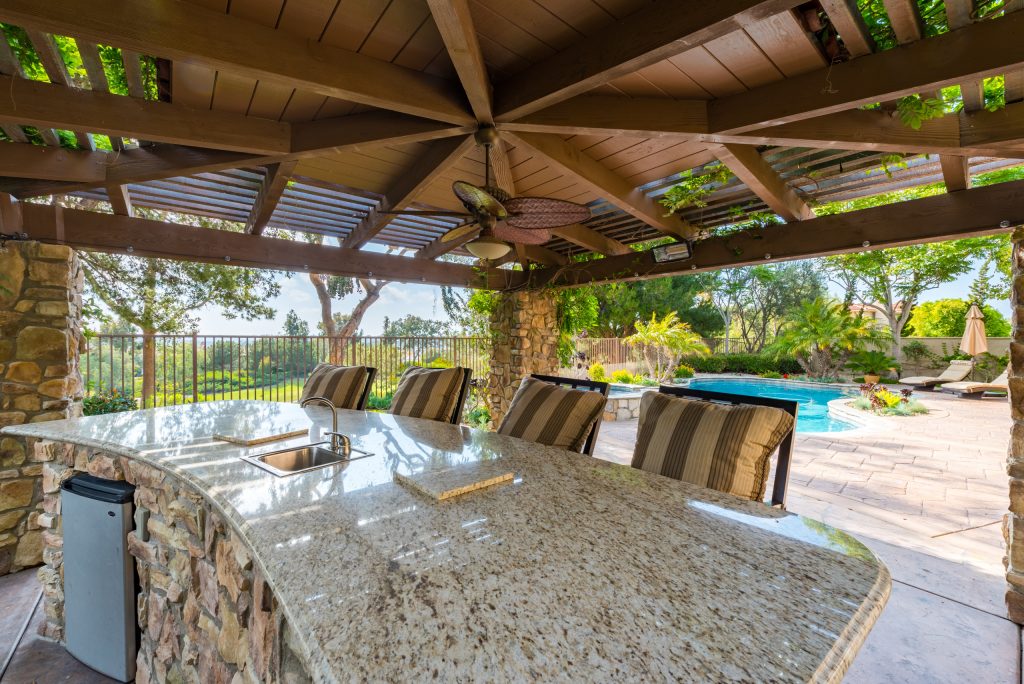 Large mid-century modern backyard stone patio kitchen photo in San Diego with a gazebo