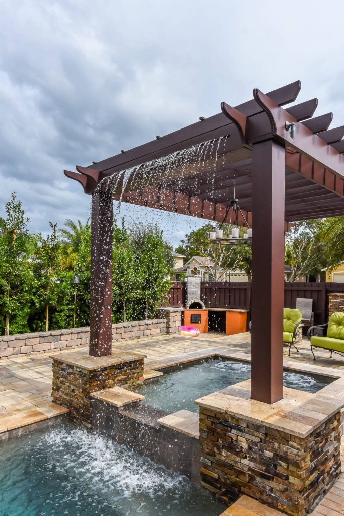 Large minimalist backyard stone and custom-shaped pool fountain photo in Orlando