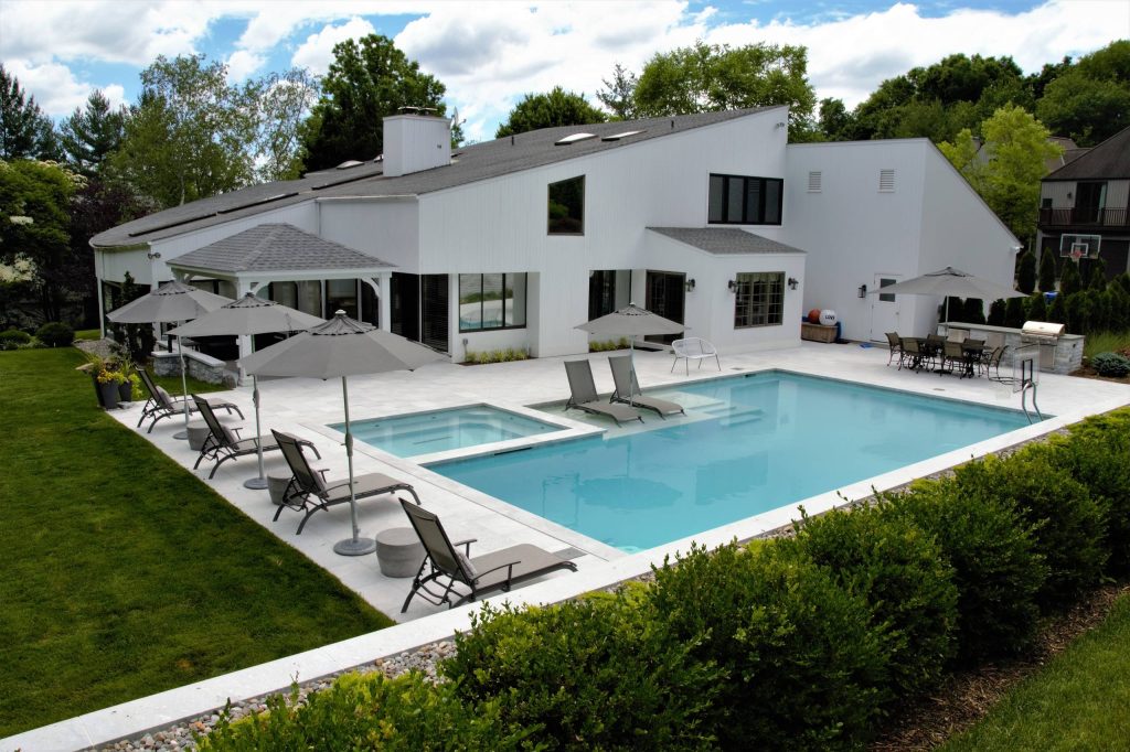 Large minimalist backyard stone and rectangular lap hot tub photo in New York