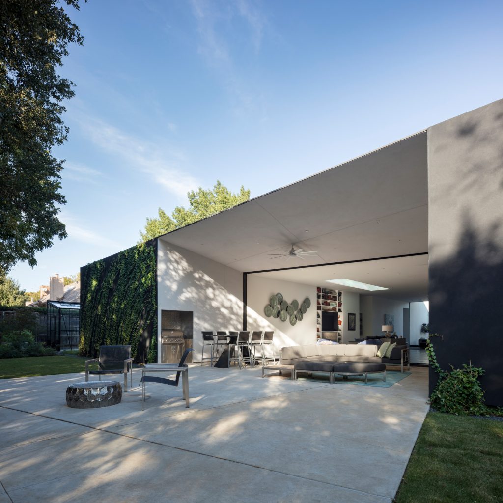 Large minimalist front yard concrete patio kitchen photo in Dallas with a roof extension