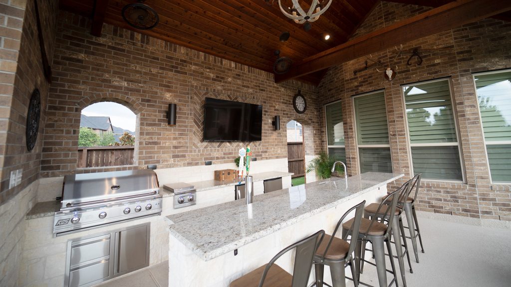 Large mountain style backyard concrete patio kitchen photo in Houston with a roof extension