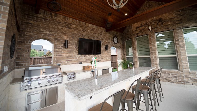 Large mountain style backyard concrete patio kitchen photo in Houston with a roof extension