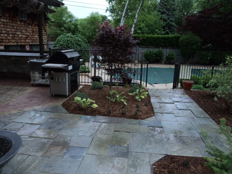Large mountain style backyard stone patio kitchen photo in Detroit with a pergola