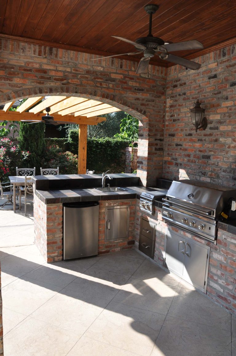 Large mountain style backyard stone patio kitchen photo in New Orleans with a roof extension
