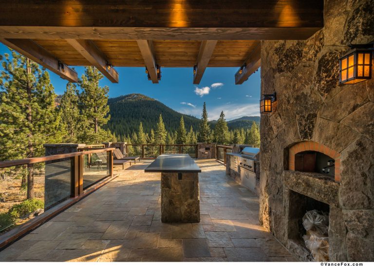 Large mountain style backyard stone patio kitchen photo in Sacramento with a roof extension
