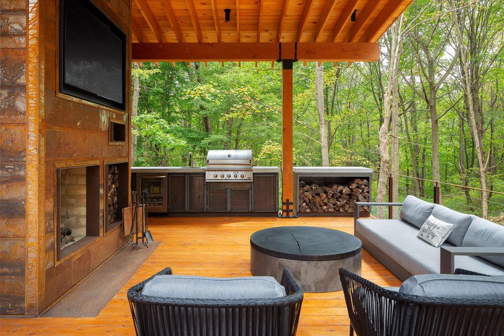 Large mountain style side yard outdoor kitchen deck photo in Other with a roof extension