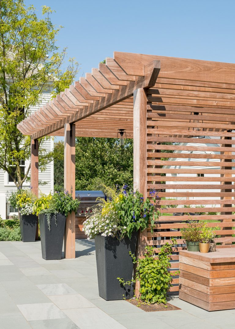 Large transitional backyard stone patio kitchen photo in Burlington with a pergola